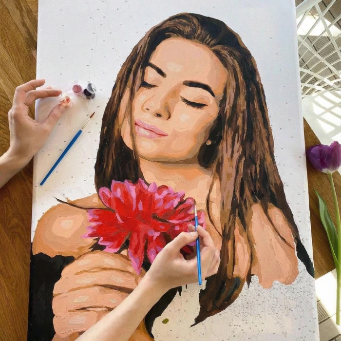 Close up of a personalized paint by numbers canvas of a woman with a red flower, showing detailed brushwork for adult DIY art.