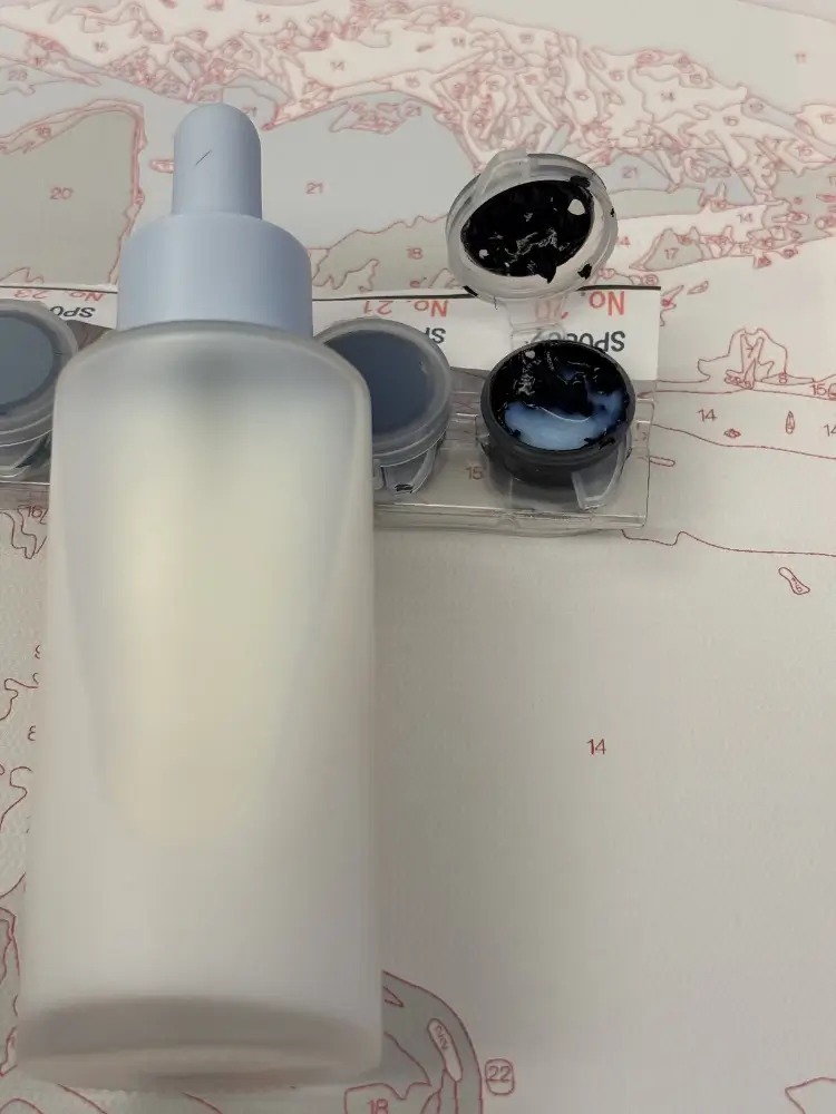 A dropper bottle of acrylic flow medium next to a Custom Paint by Numbers paint pot.