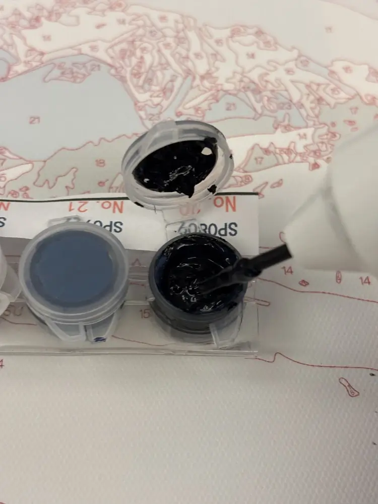 Stirring acrylic paint and flow medium inside a small pot using a mini electric paint mixer.