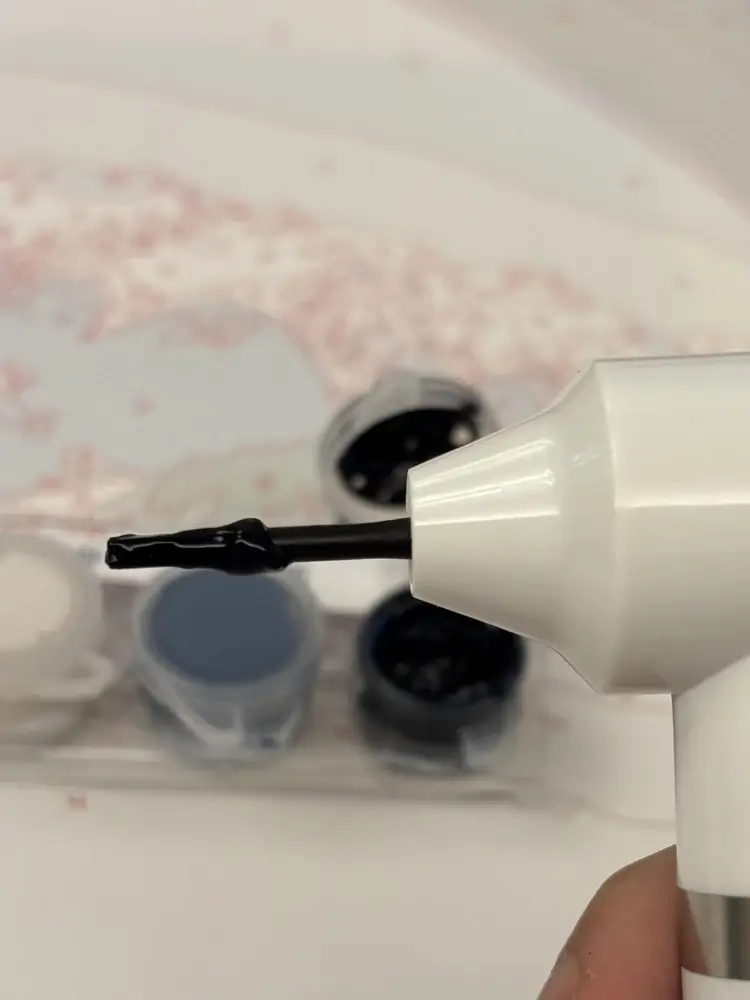 Smooth and creamy dark acrylic paint consistency on the tip of an electric mixer for the flow method.