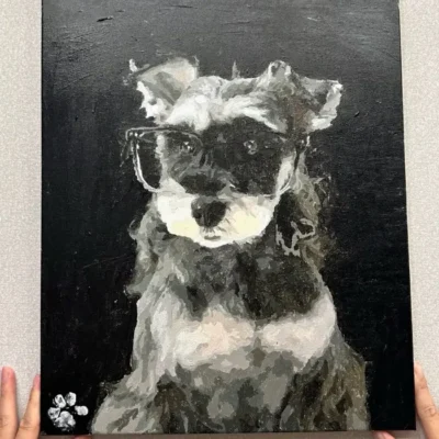 Close up of a completed personalized pet portrait canvas showing a black and white Schnauzer with glasses and a white paw print.