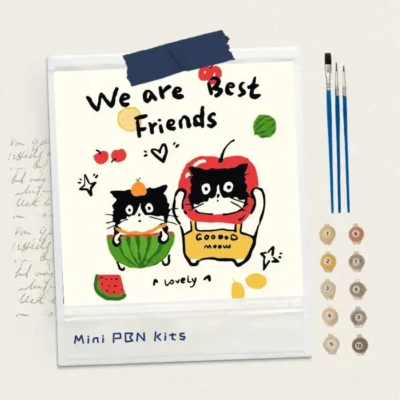 Finished 8x8 mini paint by numbers artwork of two cute cats wearing fruit costumes, with text "We are Best Friends", displayed with acrylic paint pots and brushes.
